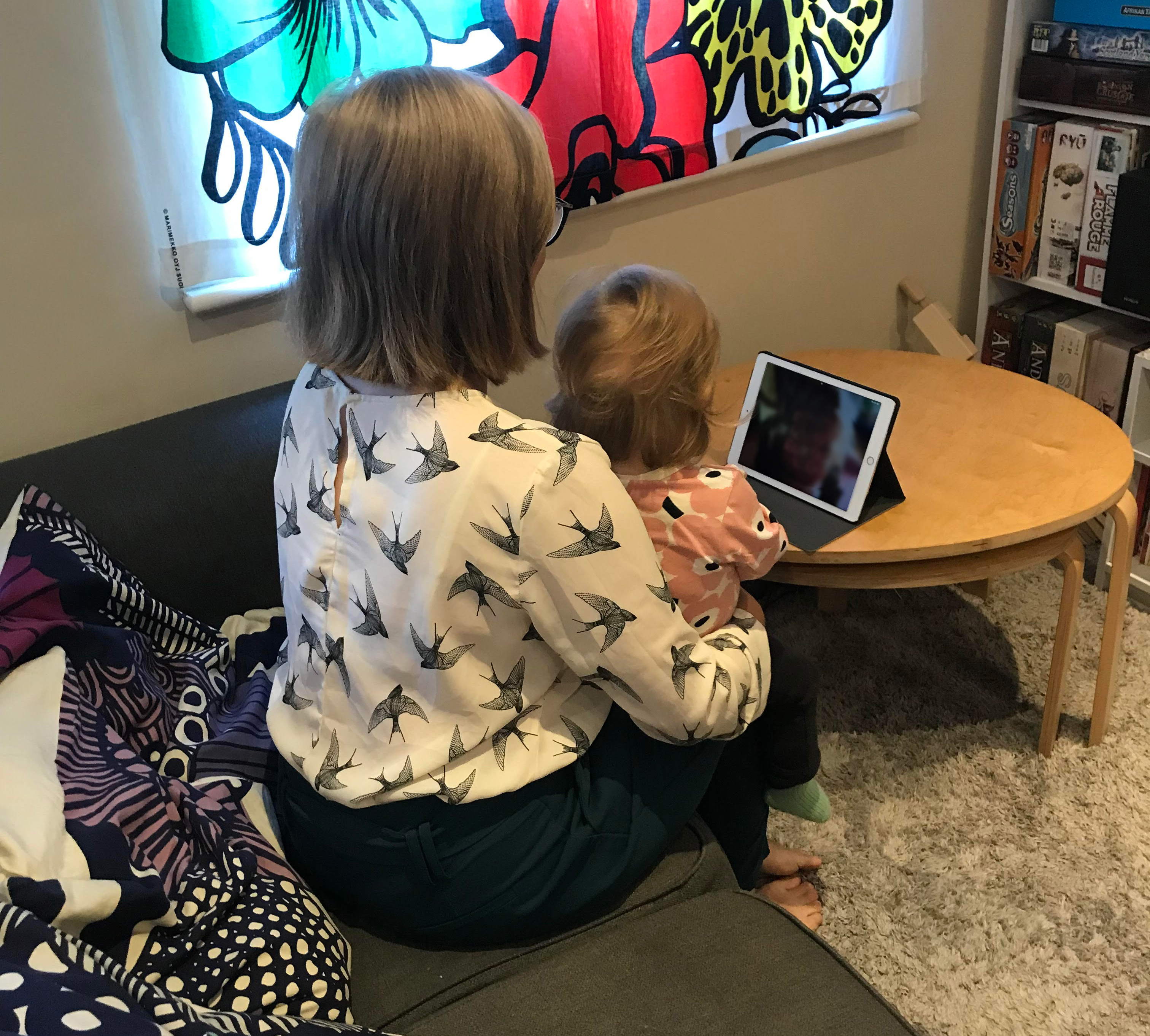 blond female with small child sat on lap looking at a tablet
